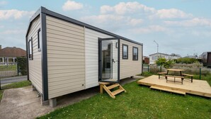 A single-story mobile home with a sliding door, a small deck, and a picnic table.