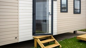 A mobile home with a sliding door, a small wooden step, and a window.