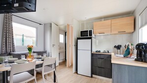 A compact kitchen with a microwave, refrigerator, and a dining area with a table and chairs.