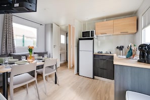 A compact kitchen with a microwave, refrigerator, and a dining area with a table and chairs.