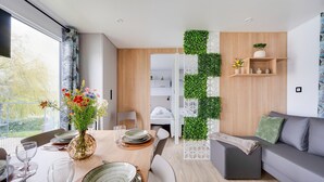 Ein moderner Essbereich mit Holztisch, weißen Stühlen und einem Blumenstrauß.