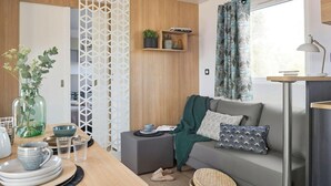 Ein modernes Wohnzimmer mit einer Couch, einem Couchtisch, einer Zimmerpflanze und einem Bücherregal.