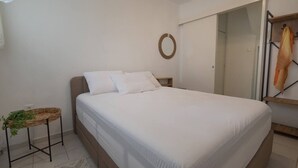 Un dormitorio con cama, una mesita de noche con una planta, un adorno circular en la pared y un armario.
