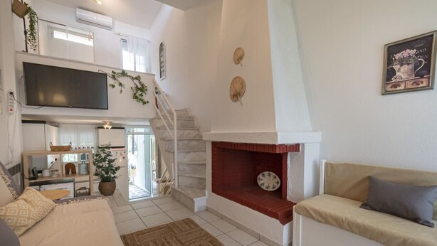 Una sala de estar moderna con chimenea, un sofá, un televisor y una escalera que sube a un nivel superior.