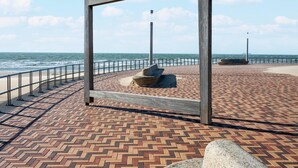 Un paseo marítimo con suelo de ladrillo estampado, barandilla de metal y estructura de madera.