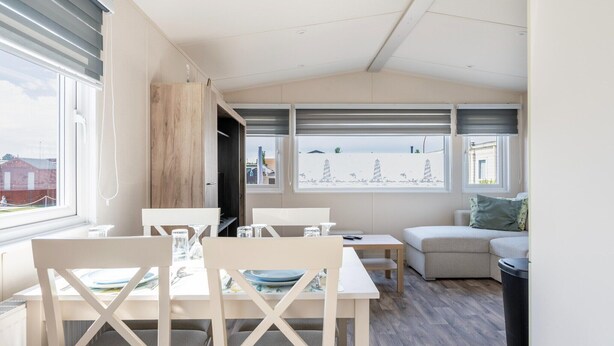 Ein modernes Interieur mit Essbereich, einer Couch und Blick ins Freie.