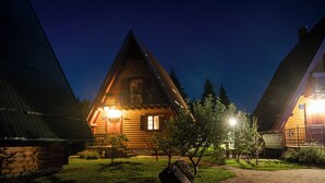 Une cabane en rondins avec un toit en pente, une véranda et une entrée éclairée.