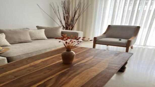 Uma sala de estar moderna com uma mesa de centro de madeira, um sofá e uma poltrona.