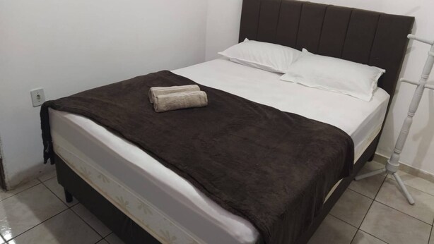 A single bed with a dark headboard, white bedding, and a brown blanket. - 001 - Apartment Close to the Center (Vitoria da Conquista)