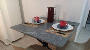 A dining table with a granite top, two chairs, a red mug, a glass, and a pitcher. - 001 - Apartment Close to the Center (Vitoria da Conquista)