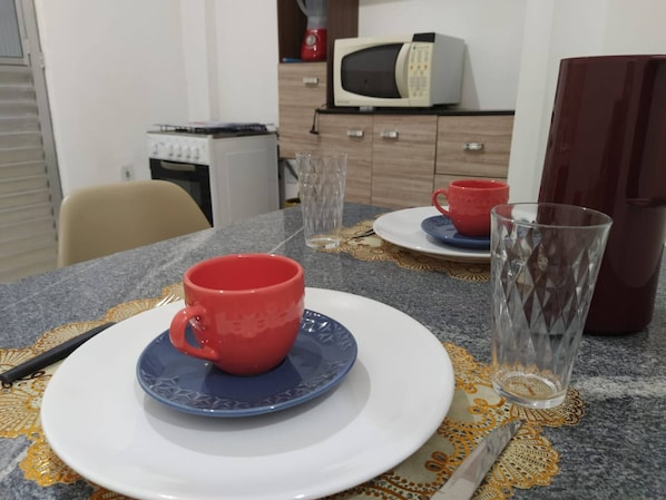A dining table with a red mug, a clear glass, and a white plate.