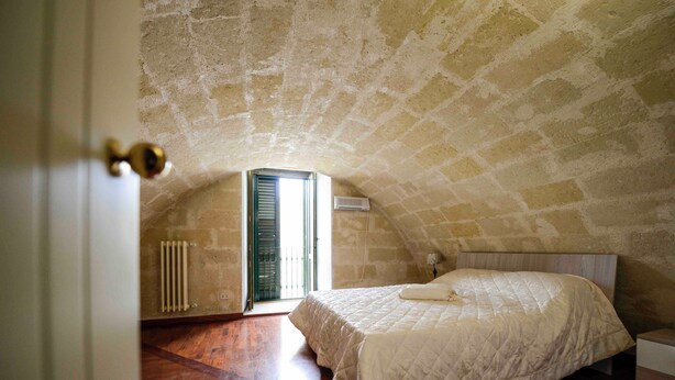 A bedroom with a sloped ceiling, a bed, a radiator, and a door. - VACATION HOME " THE BELVEDERE ON THE STONES " CIN: IT077014C202430001 (Matera)