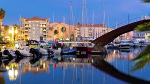 Un puerto deportivo con barcos amarrados, un puente y edificios al fondo.