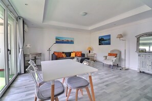 Ein geräumiges Zimmer mit Esstisch, Stühlen, einer Couch und einer Lampe.
