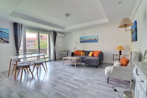 Ein modernes Wohnzimmer mit Sofa, Couchtisch und Essbereich mit Stühlen.