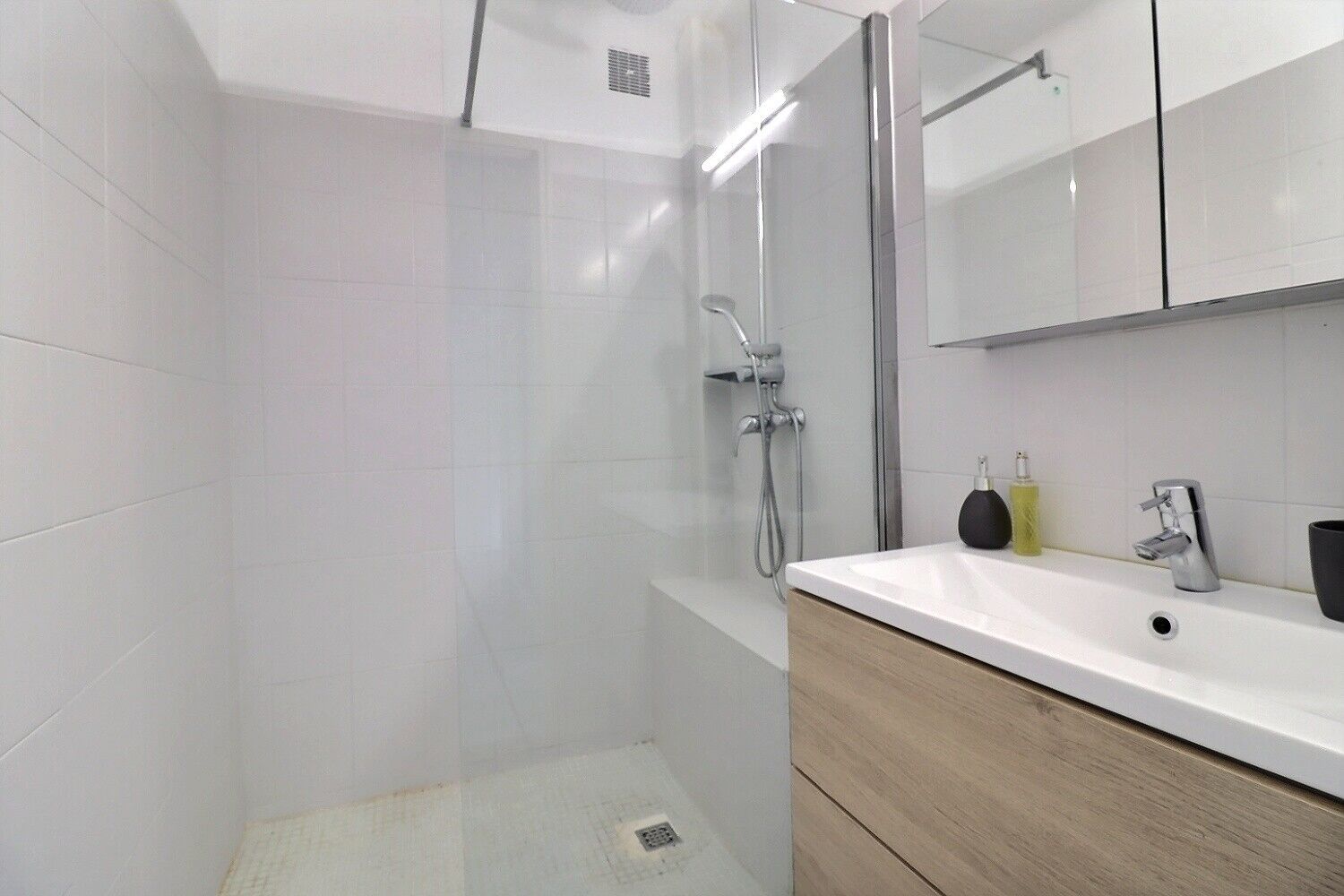 Une salle de bain moderne avec une douche, un lavabo et un miroir.