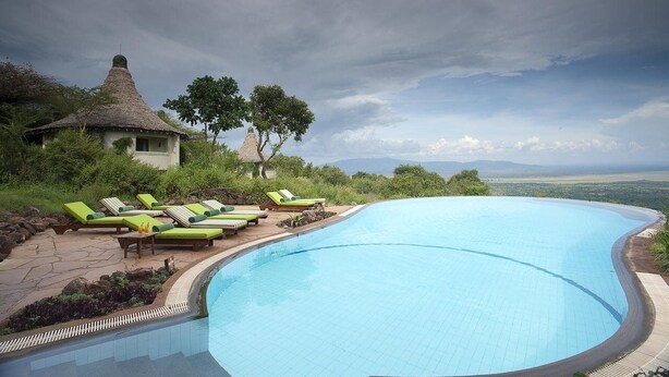 A swimming pool with lounge chairs, a small hut, and a view of the landscape. - Lake Manyara Serena Safari Lodge (Lake Manyara National Park)