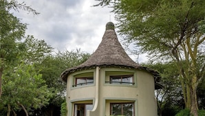 Un piccolo edificio a un piano con tetto a cono, immerso nel verde.