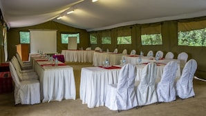 Una sala conferenze con tende, tavoli rotondi, sedie e un podio.