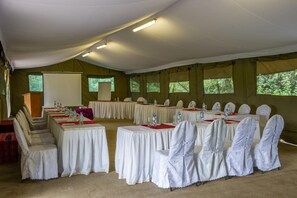 Ein Zelt-Konferenzraum mit runden Tischen, Stühlen und einem Rednerpult.