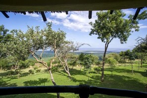 A view from a covered area with trees and a distant landscape. - Lake Manyara Serena Safari Lodge (Lake Manyara National Park)