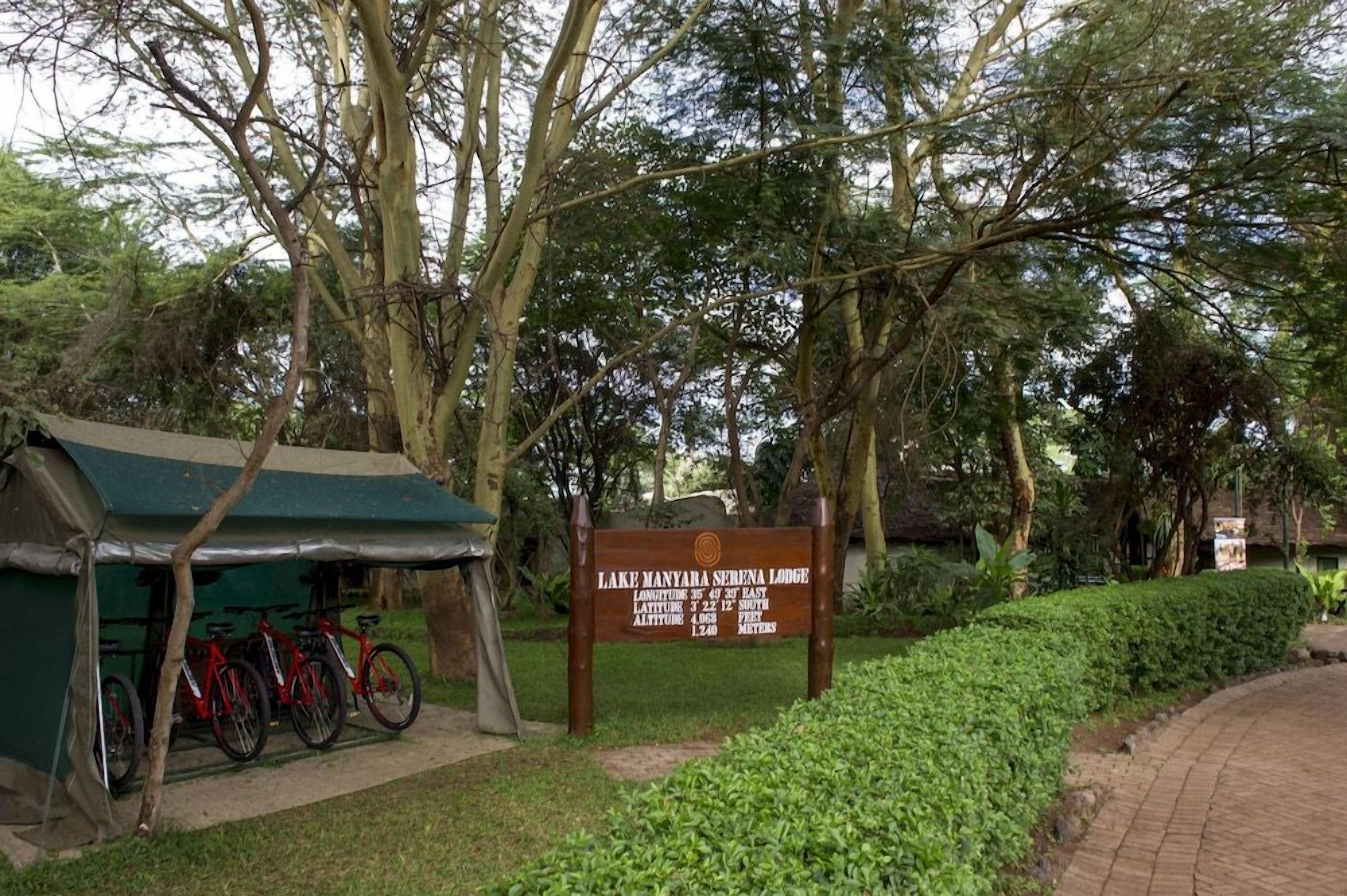 A sign for Lake Manyara Serena Lodge with a tent and bicycles nearby.