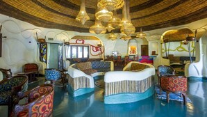 A room with a unique curved ceiling, patterned chairs, and a central seating area. - Lake Manyara Serena Safari Lodge (Lake Manyara National Park)