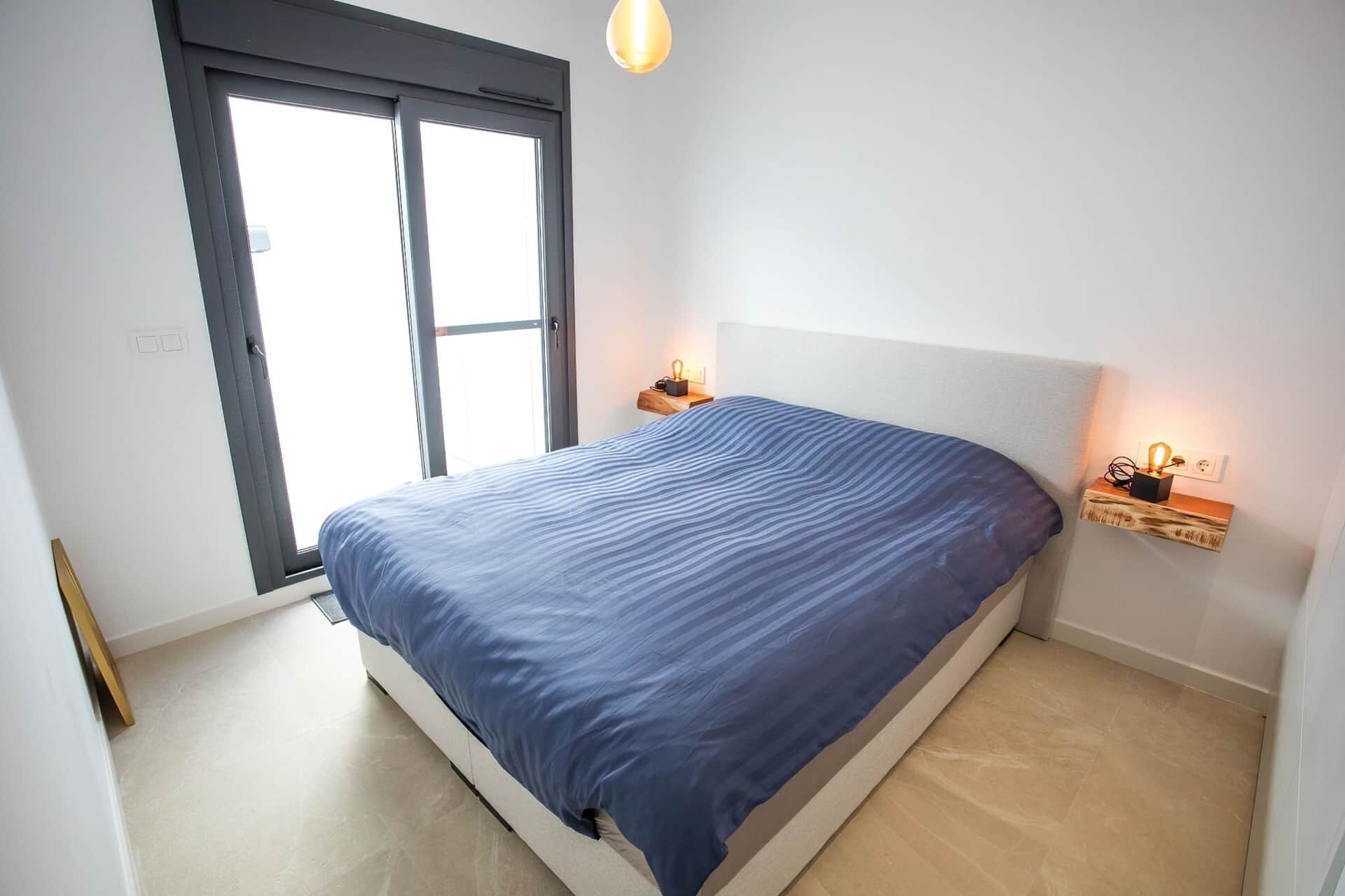 Un dormitorio con cama, ventana y lámparas de noche.