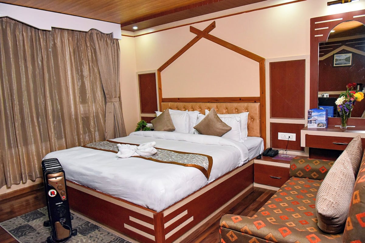 A hotel room with a wooden bed, a desk, a chair, and a large window with curtains.