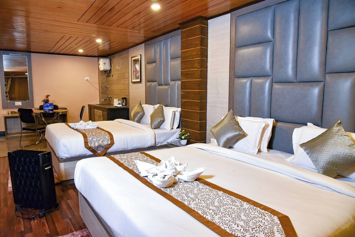 A hotel room with two beds, a desk, a chair, and a large mirror.