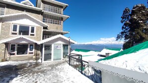 A multi-story building with a stone facade, large windows, and a green awning. - Anutri Hotels & Resorts  (Darjeeling)