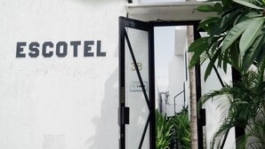 Pared blanca con la palabra 'ESCOTEL' escrita en letras negras.