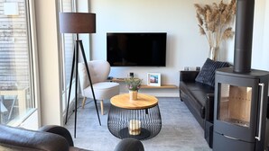 Una sala de estar con sofá, televisión, chimenea y una mesa de centro redonda.