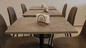 Ein Essbereich mit einem Marmortisch, schwarzen Stühlen und einer Uhr an der Wand.