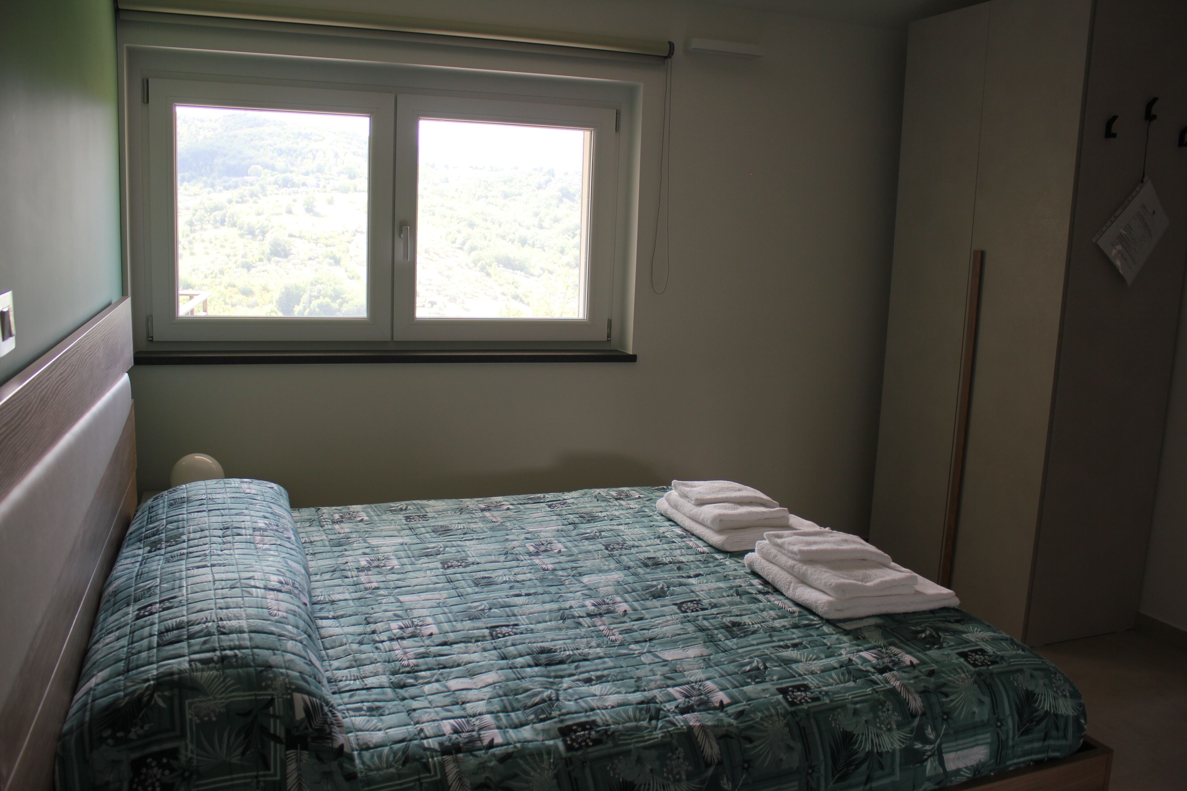 A bedroom with a bed, a window, and a wardrobe.