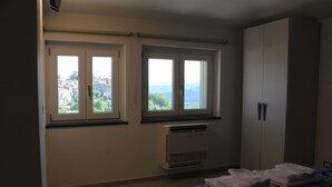 Ein Schlafzimmer mit einem Bett, zwei Fenstern, einer Klimaanlage und einem Kleiderschrank.