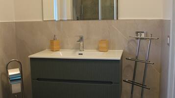 Un baño con inodoro, lavamanos con espejo y toallero.