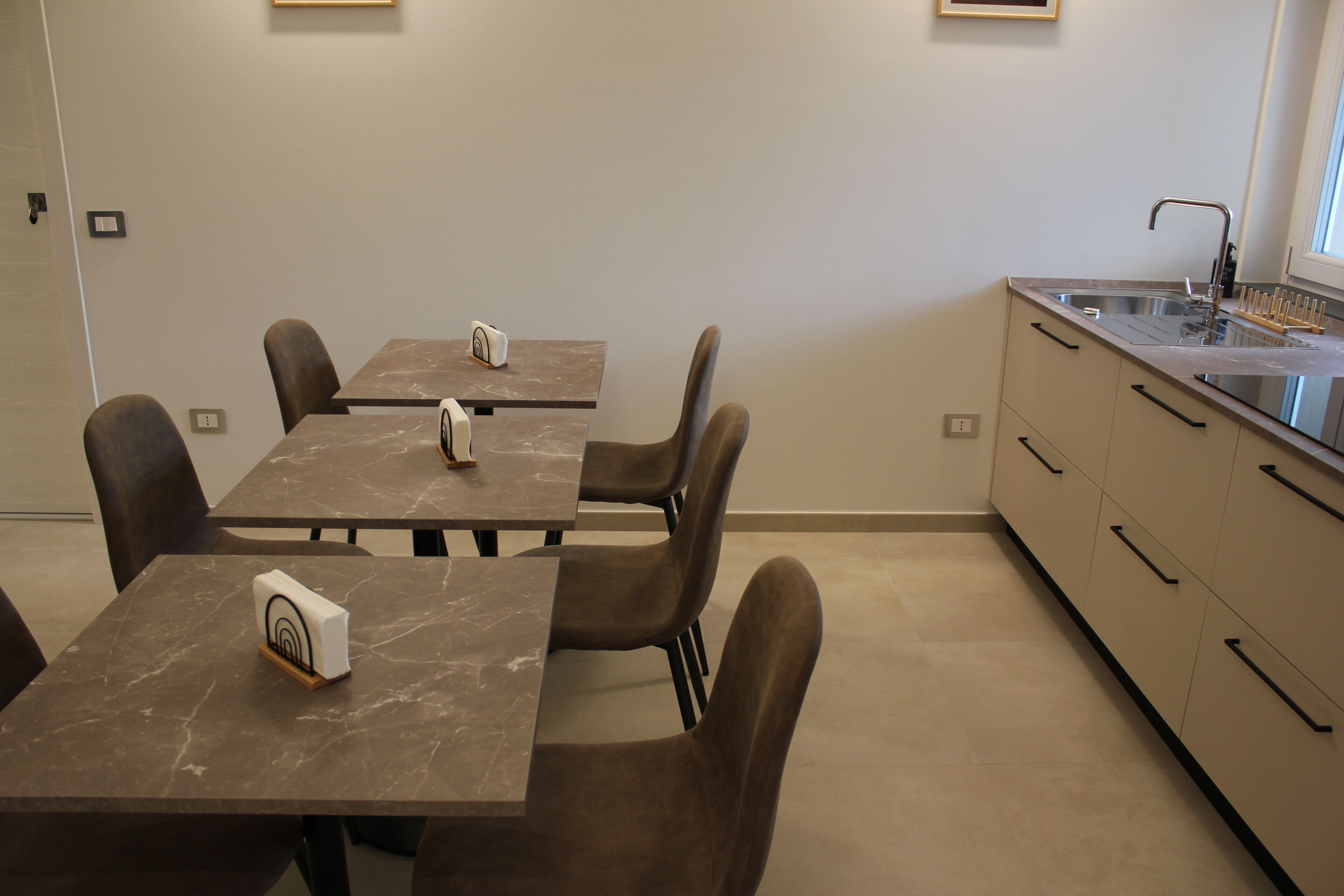 Une cuisine moderne équipée de deux tables à manger, de chaises, d’un évier et de placards.