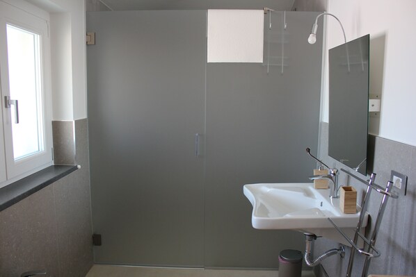 A modern bathroom with a shower, sink, and mirror. - TENUTA BELVEDERE (Fornelli)