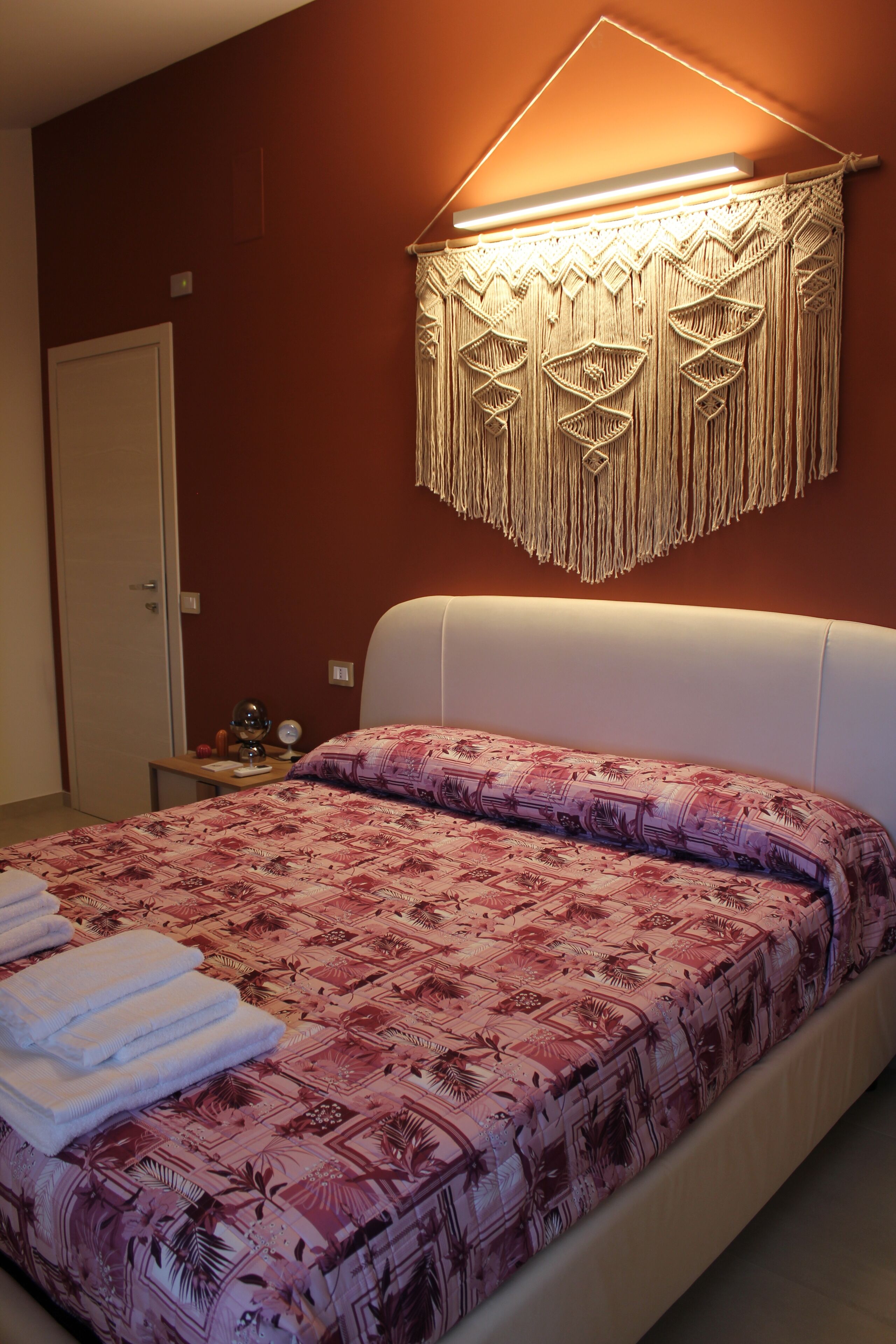 Ein Schlafzimmer mit einem Bett, einem Nachttisch, einer Wandleuchte und einer Tür.