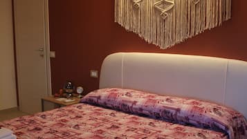 Ein Schlafzimmer mit einem Bett, einem Nachttisch, einer Wandleuchte und einer Tür.