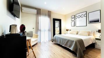 Habitación de hotel moderna con cama, mesita de noche, lámpara y escritorio con cafetera.