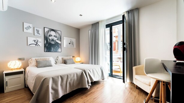 Een moderne hotelkamer met een bed, nachtkastjes, een bureau en een stoel.