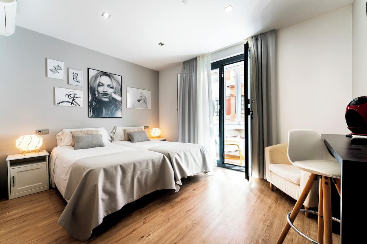 A modern hotel room with a bed, bedside tables, a desk, and a chair.