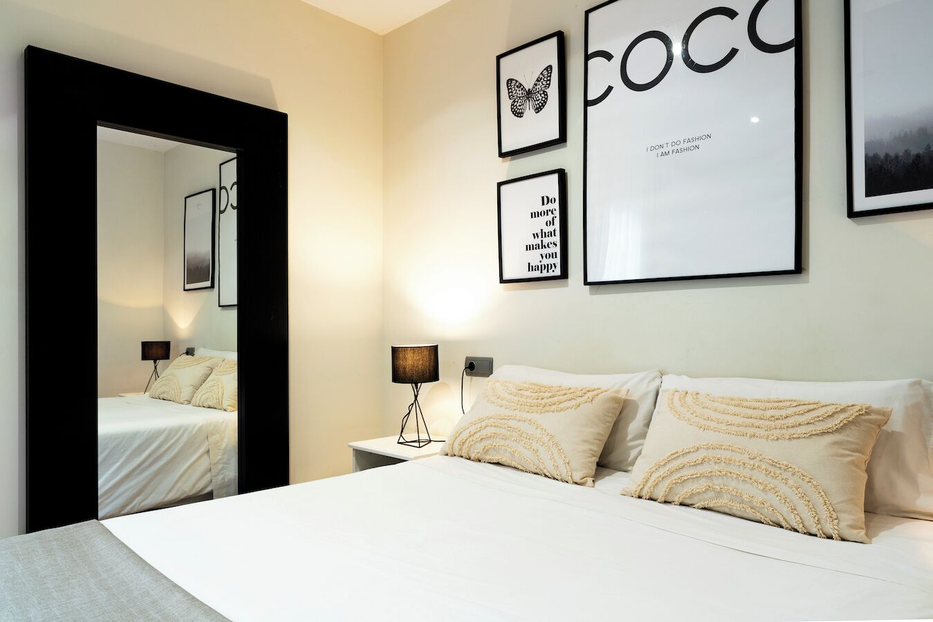 A bedroom with a bed, a nightstand, a lamp, and wall art.