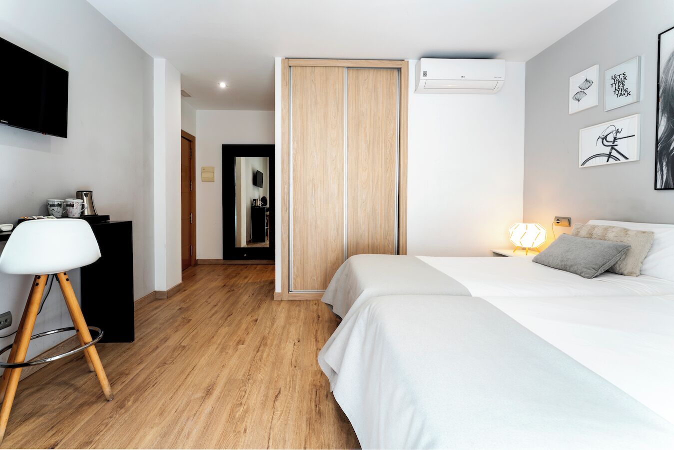 A bedroom with a bed, bedside table, lamp, and a TV mounted on the wall.