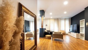 Een moderne woonkamer met een grote spiegel, houten vloeren en een televisietoestel op een kast.