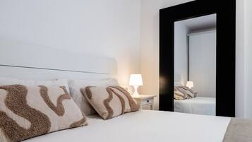 A hotel room with a bed, two bedside lamps, a nightstand, and a large mirror.