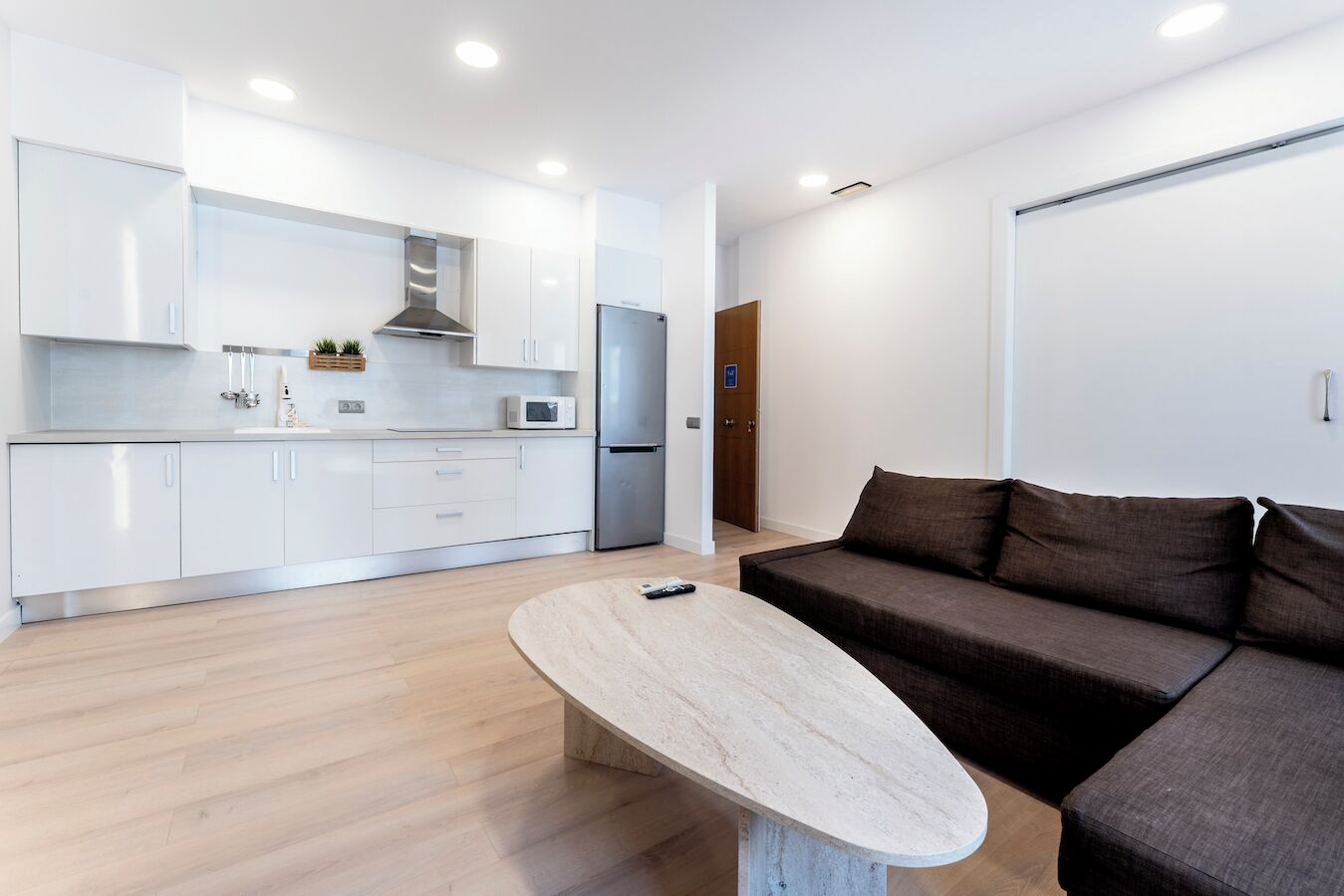 A modern kitchen with white cabinets, a stainless steel range hood, and a built-in microwave.