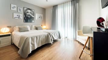 A bedroom with a bed, bedside tables, a desk with a chair, and a window with curtains.